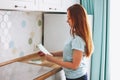 Young woman designer with long red hair holding color samples in bright kitchen at home Royalty Free Stock Photo