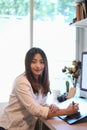 Young woman designer using graphics tablet and smiling to camera at workplace. Royalty Free Stock Photo