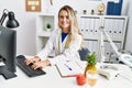 Young woman dietician smiling confident using computer at clinic Royalty Free Stock Photo