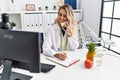 Young woman dietician talking on telephone writing on document at clinic