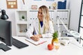 Young woman dietician writing on document at clinic Royalty Free Stock Photo