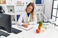 Young woman dietician writing on document at clinic