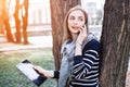 Young woman with digital tablet in hand talking on mobile phone with boyfriend before a meeting with it. Attractive girl Royalty Free Stock Photo