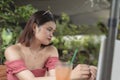 A young woman dining at an al fresco cafe looks down at the ground as she is troubled with her thoughts