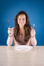 Young woman at the dinner table with fork and knife Royalty Free Stock Photo