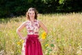 Young woman in dirndl standing in field of flowers Royalty Free Stock Photo