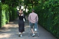 A young woman and a disabled guy walk along the green alley of the park Royalty Free Stock Photo