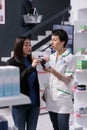 Young woman discussing multivitamin choice with drugstore assistant