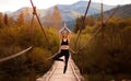 Young woman do yoga balance exercises. Yoga meditation on bridge over river with mountains background. Concept of Royalty Free Stock Photo