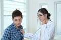 Young woman doctor auscultating male with stethoscope