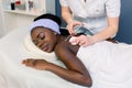 Young woman doctor cosmetologist injects mesotherapy or special solution on the back of pretty African woman in spa