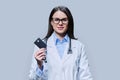 Young woman doctor holding credit card on light gray background Royalty Free Stock Photo