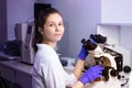 A young woman doctor (laboratory assistant) conducts a study of a blood sample on a microscope. Royalty Free Stock Photo