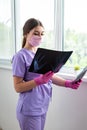 Young woman doctor looking at xray radiography images at clinic. Physician, surgeon reviewing scan of patient bones