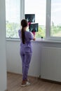 Young woman doctor looking at xray radiography images at clinic. Physician, surgeon reviewing scan of patient bones