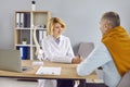 Young woman doctor with medical spine model on desk talking to senior man patient Royalty Free Stock Photo