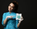 Young woman doctor nurse in blue uniform and protective latex gloves shows points finger at special medical tools