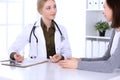 Young woman doctor and patient at medical examination in hospital office. Khaki colored blouse of therapist looks good