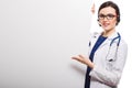 Young woman doctor with stethoscope and headphones with a blank billboard in white uniform on white background Royalty Free Stock Photo