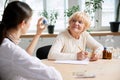 Young woman, doctor, therapist prescribing pill, meds to her senior female patient. Modern hospital, office. Royalty Free Stock Photo