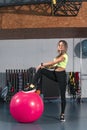 Young woman does an exercise with fitness ball. Young woman works out in the fitness center with pilates ball