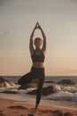 Young woman does yoga for healthy lifestyle on sea beach Royalty Free Stock Photo