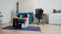 Young woman does yoga at home bending knees to her chest in pindasana pose