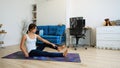 Young woman does yoga at home bending knees to her chest in pindasana pose