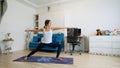 Young woman does yoga at home bending knees to her chest in pindasana pose