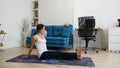 Young woman does yoga at home bending knees to her chest in pindasana pose