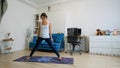 Young woman does yoga at home bending knees to her chest in pindasana pose