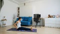 Young woman does yoga at home bending knees to her chest in pindasana pose