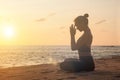 Slim woman does yoga in lotus posture on tropical sea coast or ocean beach outdoors on sunset Royalty Free Stock Photo