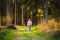 Young woman and dog running together on country in forest. Cheerful female exercising outdoor with her pet Royalty Free Stock Photo