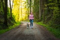 Young woman and dog running together on country in forest. Cheerful female exercising outdoor with her pet Royalty Free Stock Photo
