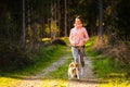 Young woman and dog running together on country in forest. Cheerful female exercising outdoor with her pet Royalty Free Stock Photo