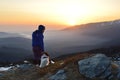 Young woman and dog at sunrise high in the mountain