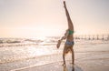 Young woman doing acrobatic exercise on coast of sea on beach Royalty Free Stock Photo