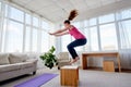 Young woman doing box jump exercise in living room at home, copy space. Jumping squats. Royalty Free Stock Photo