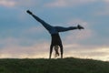 Young woman doing cartwheel on the grass Morning workout beautiful sunrise Royalty Free Stock Photo