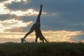 Young woman doing cartwheel on the grass Morning workout beautiful sunrise Royalty Free Stock Photo