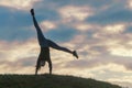 Young woman doing cartwheel on the grass Morning workout beautiful sunrise Royalty Free Stock Photo