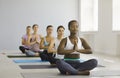 Young woman doing easy asanas, breathing exercises and meditating during group yoga. Royalty Free Stock Photo