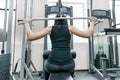 Young woman doing exercises for the back on a fitness machine in the gym, view from the back. Fitness, sport, training, people Royalty Free Stock Photo