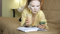 Young woman doing facial mask mask with cleansing mask, clicks on couch with smartphone at home