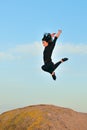 Young woman doing gymnastic jump on a rock against a blue sky Royalty Free Stock Photo