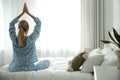 Young woman doing gymnastics on bed at home, back view. Morning fitness Royalty Free Stock Photo