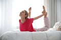 Young woman doing gymnastics on bed at home. Morning fitness Royalty Free Stock Photo