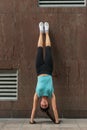 Young woman doing handstand exercise against the wall on the city street. Royalty Free Stock Photo