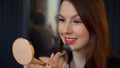 Young woman doing make up. Girl with red lipstick applies powder with brush. Royalty Free Stock Photo